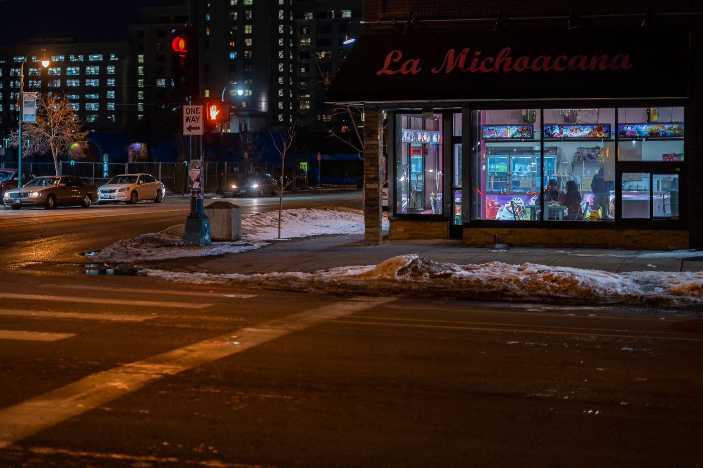 La Michoacana ice cream shop is illuminated at night on Lake Street in Minneapolis. This establishment is known for serving traditional Mexican ice cream and treats, functioning as a cultural gathering point for the community. Lake Street is a significant commercial corridor in Minneapolis, recognized for its diverse businesses and its role as a central hub, particularly noted for its involvement in the 2020 Minneapolis Uprising.