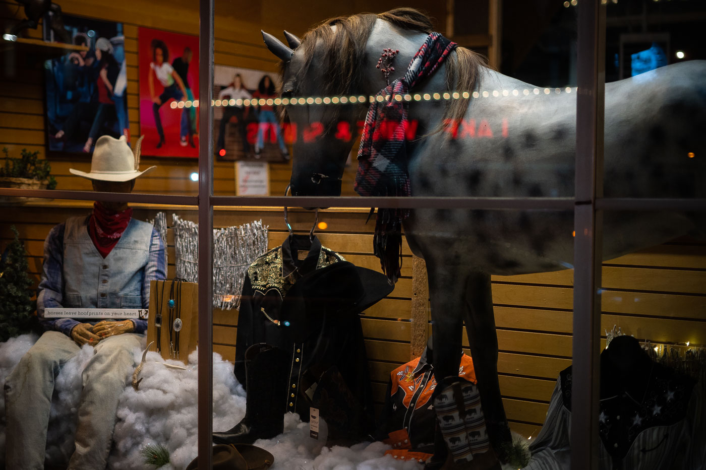 The Schatzlein Saddle Shop, a long-standing retailer of Western wear, displays its merchandise in its storefront window on Lake Street in Minneapolis in March 2022. The shop has been a fixture in the city for decades, providing clothing and gear for equestrians and enthusiasts of Western culture. The window display features a mannequin dressed in traditional Western attire, alongside boots, saddles, and other accessories, all arranged around a life-sized model of a horse. This display reflects the shop's commitment to preserving and promoting the Western lifestyle within an urban environment.