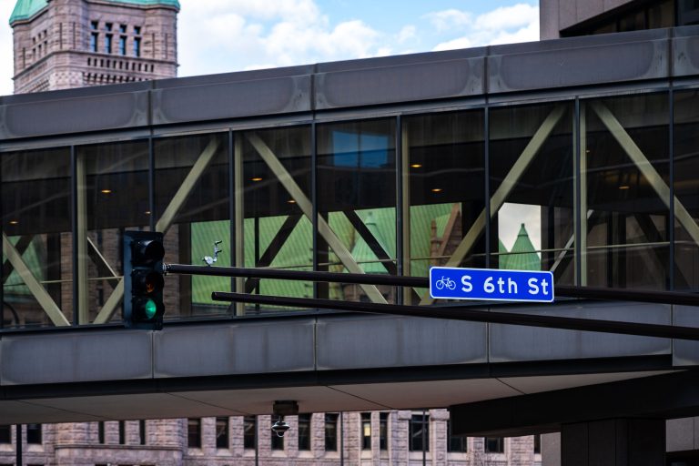 S 6th Street Skyway, Downtown Minneapolis 3 S 6th Street sign on downtown Minneapolis skyway with City Hall visible behind.