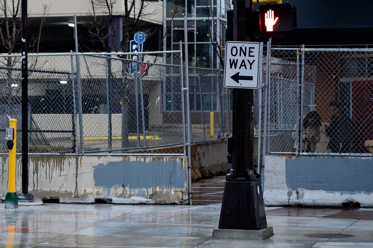 A couple stands behind security fencing surrounding sidewalks and entrances to Seven Points Mall.