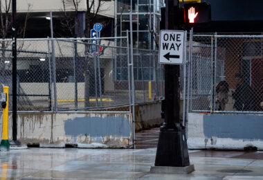A couple stands behind security fencing surrounding sidewalks and entrances to Seven Points Mall.
