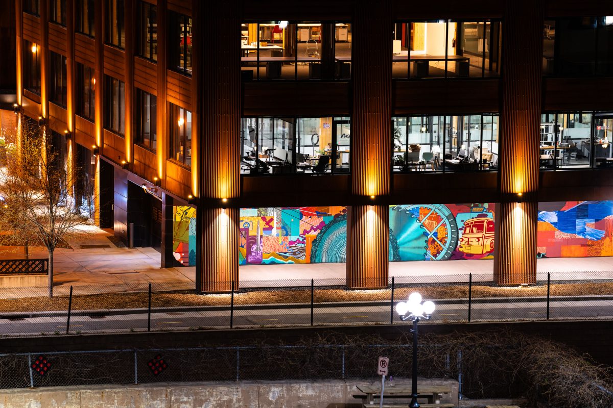Colorful mural covers the ground-floor wall of a North Loop building along Cedar Lake Trail in Minneapolis at night.