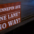 A sign in a window reading "Hennepin Ave. One Lane? No Way!"