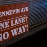 A sign in a window reading "Hennepin Ave. One Lane? No Way!"