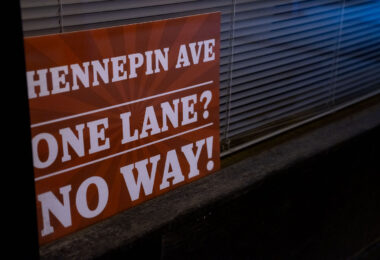 A sign in a window reading "Hennepin Ave. One Lane? No Way!"