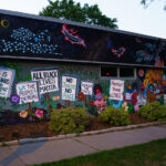 A mural in South Minneapolis. The mural shows signs reading “All Black Lives Matter” “No Justice No Peace”.