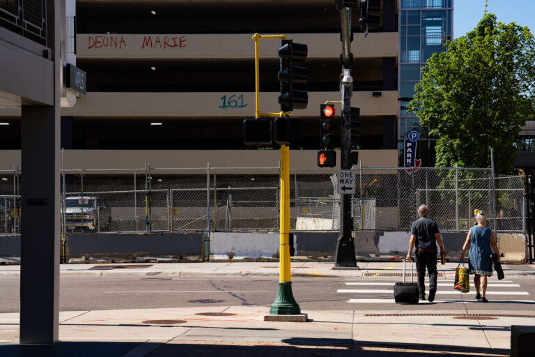 Deona Marie graffiti on Lake Street in Minneapolis 3 A couple walk across Lake Street in front of a parking garage with graffiti that reads “Deona Marie” “161”. The area has been a place of protest since the June 2021 killing of Winston Smith.Smith was killed by a federal task force serving a warrant. Protester Deona Marie was killed ten days later when a man drove his vehicle through barricades killing her.