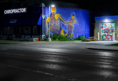 A mural on the side of a chiropractor's office in Minneapolis. "This Is Our City" written on boards at the gas station next door.