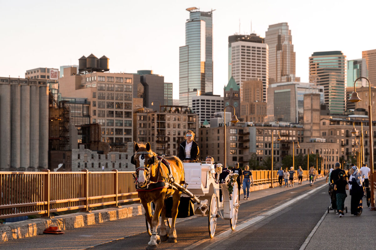 Horse-drawn carriage on Stone Arch Bridge, Minneapolis skyline