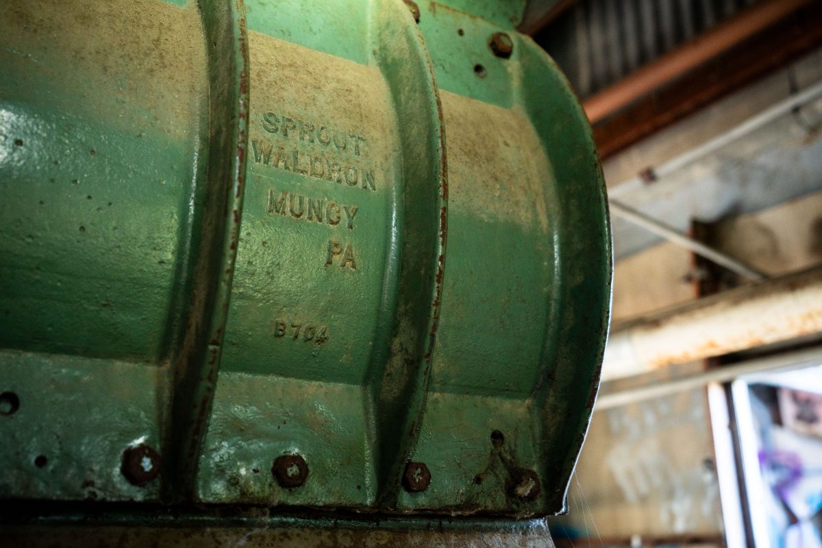 Green cast-iron sprocket labeled "Sprout Waldron Mungy PA" inside the abandoned Fruen Mill in Minneapolis.