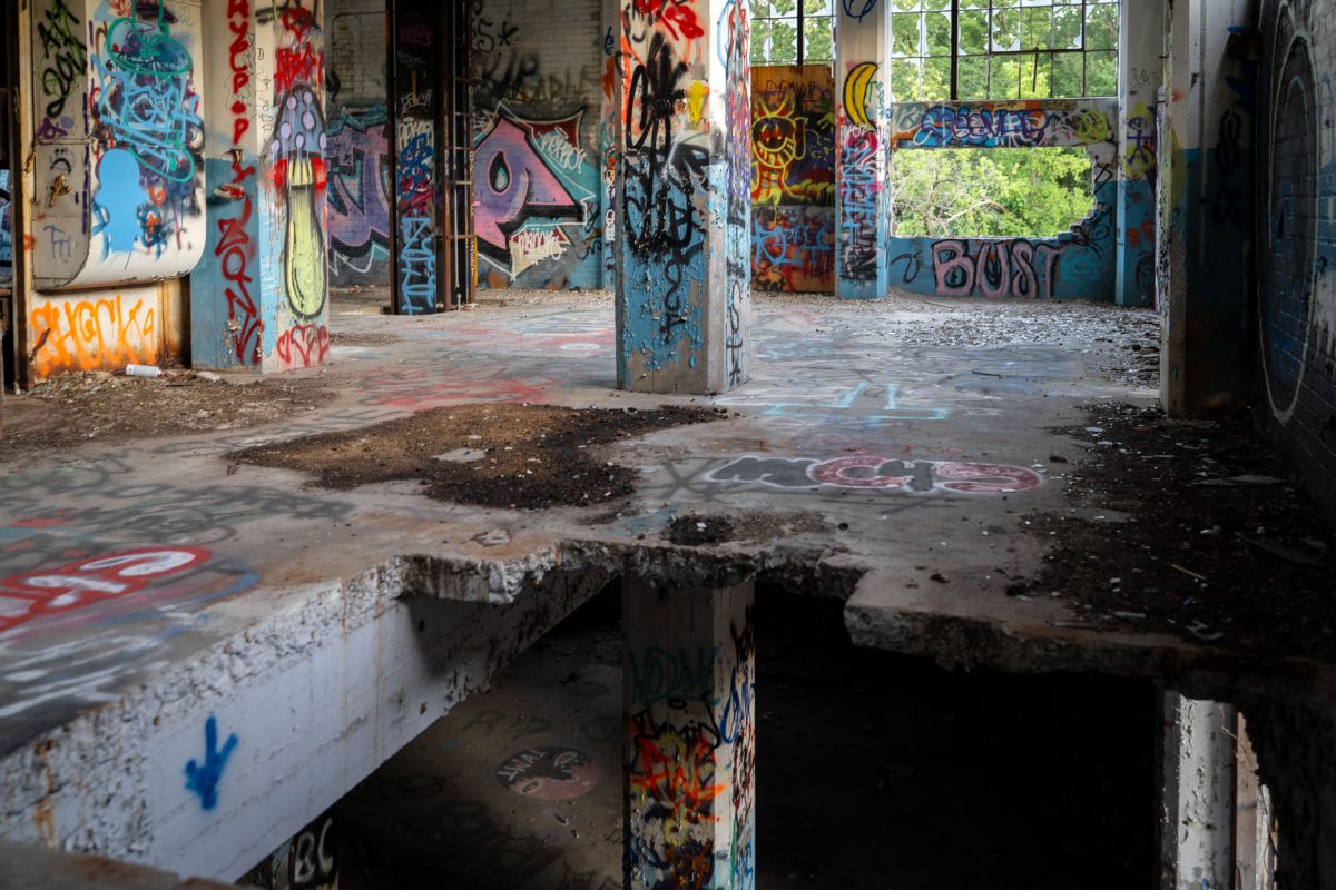 Abandoned Fruen Mill interior in Minneapolis with graffiti-covered concrete floor, structural columns, and deteriorating windows.