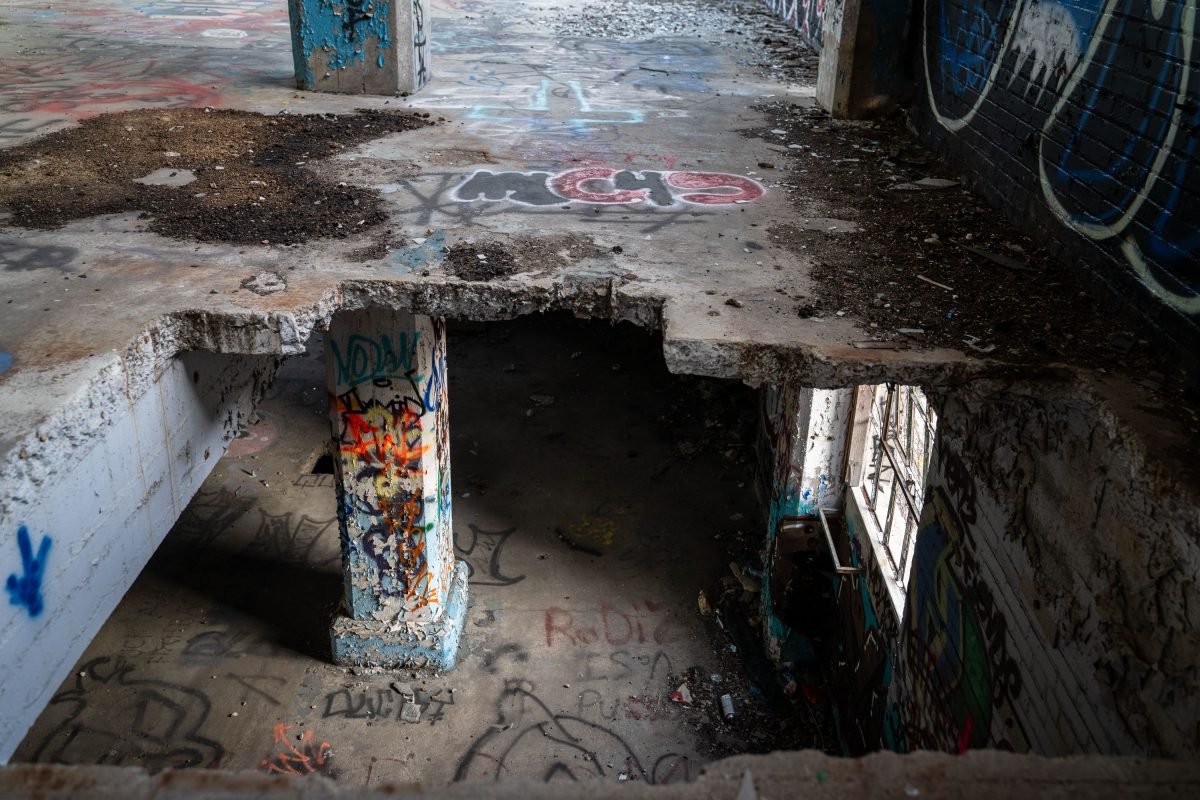 Graffiti-covered concrete basement with deteriorating support column and debris inside the abandoned Fruen Mill in Minneapolis.