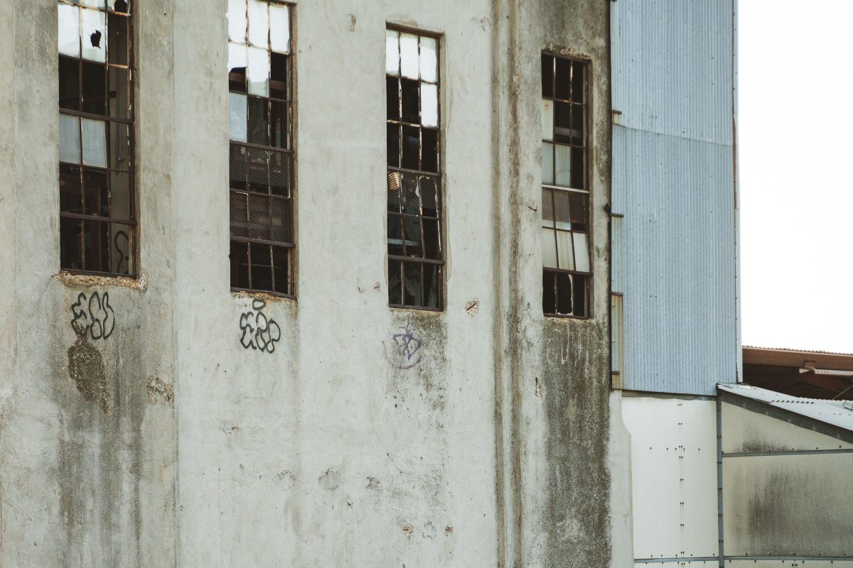 Deteriorating concrete wall with broken windows and graffiti inside the abandoned Fruen Mill in Minneapolis.