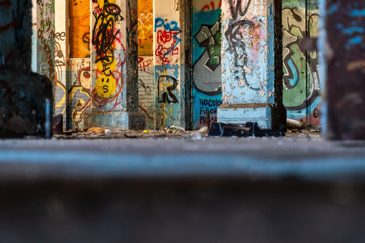 Graffitied vertical metal panels and weathered industrial columns inside the abandoned Fruen Mill.