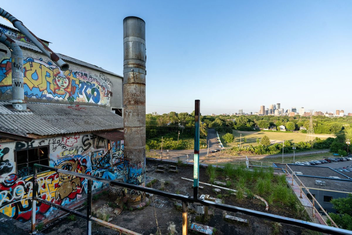 Graffiti-covered abandoned Fruen Mill industrial building with Minneapolis skyline visible in background.