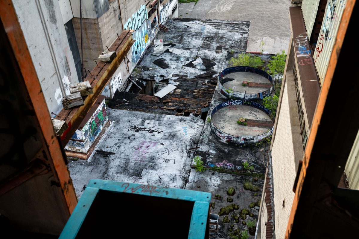 Abandoned Fruen Mill courtyard in Minneapolis with deteriorating wooden structures, rusted industrial equipment, and graffiti.