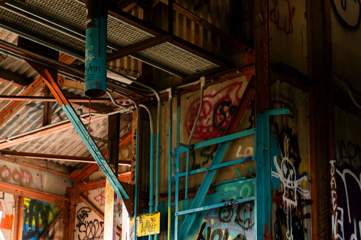 Abandoned Fruen Mill interior in Minneapolis with turquoise metal structural elements and colorful graffiti.