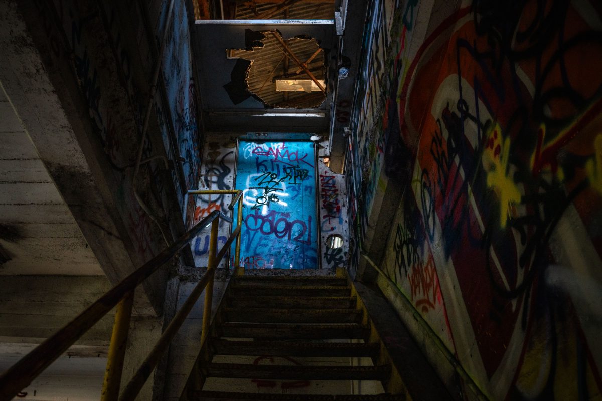 Graffiti-covered stairwell with yellow metal handrails descends into the abandoned Fruen Mill in Minneapolis.