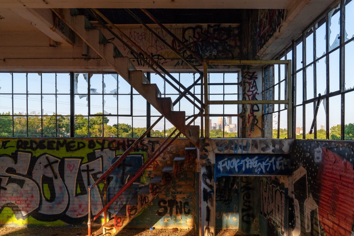 Abandoned Fruen Mill interior in Minneapolis with graffiti-covered walls, rusted metal staircase, and industrial windows.