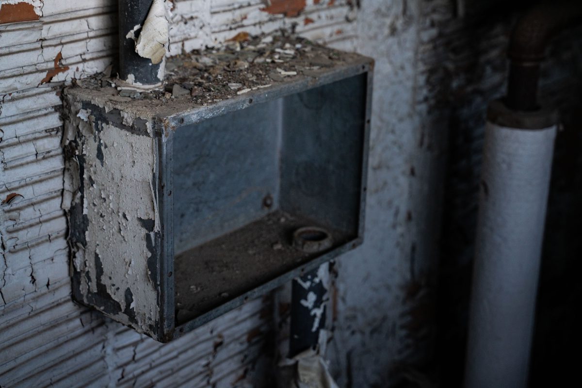 Deteriorated electrical panel mounted on peeling painted brick wall inside abandoned Fruen Mill.