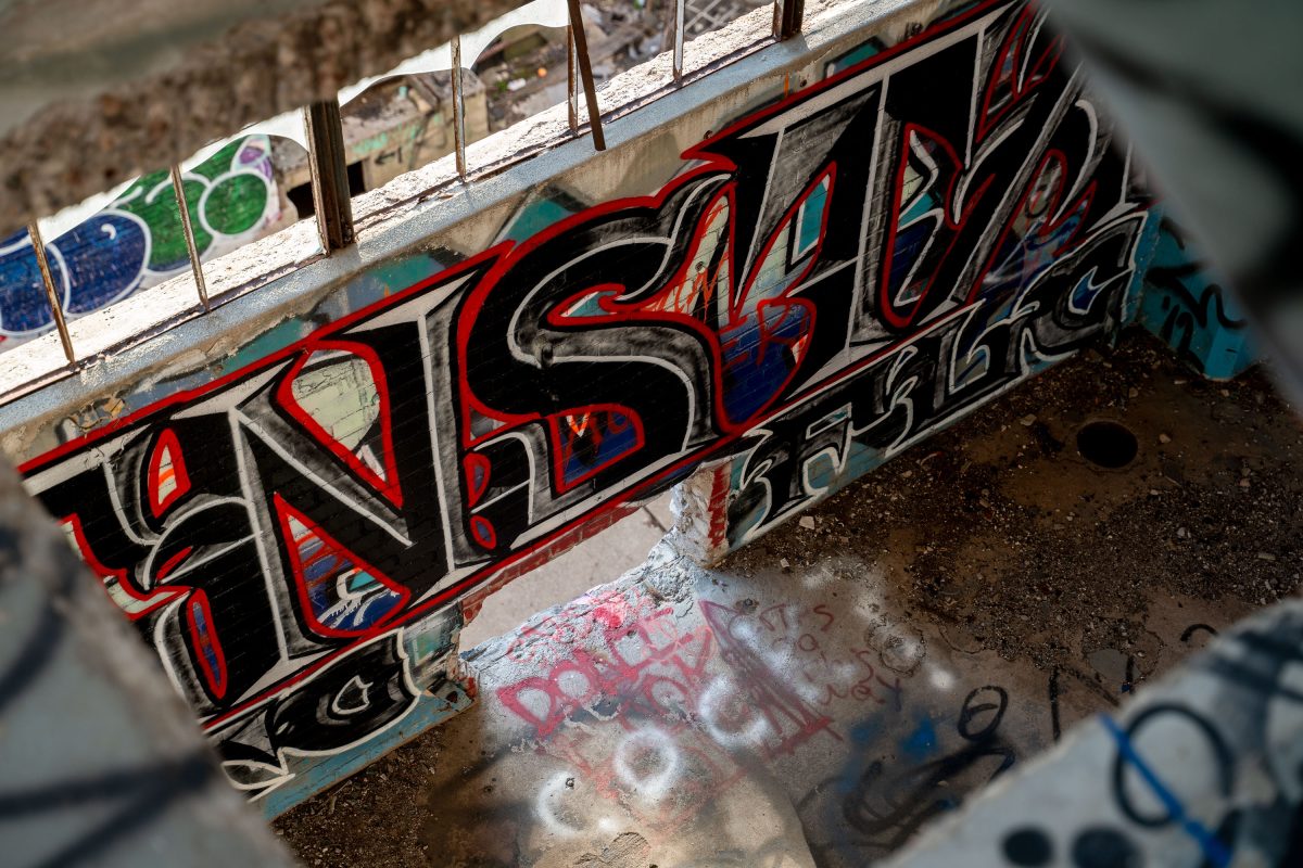 Red and black graffiti covers weathered metal industrial equipment inside the abandoned Fruen Mill in Minneapolis.