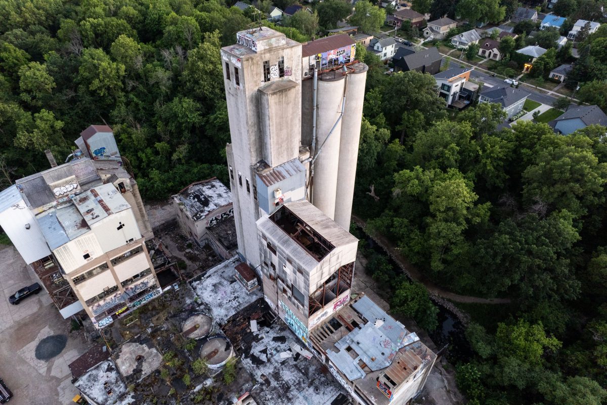 Aerial view of the abandoned Fruen Mill complex in Minneapolis surrounded by dense residential trees and buildings.