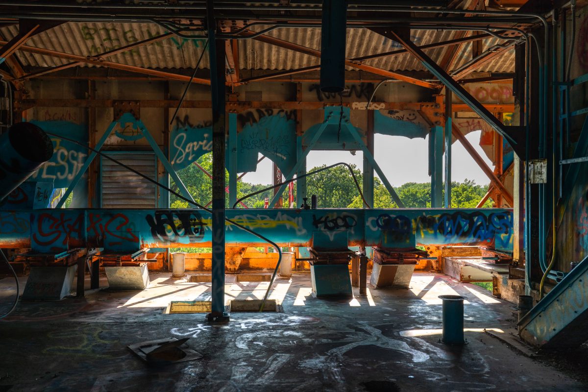 Interior of abandoned Fruen Mill in Minneapolis showing graffitied walls, rusted machinery, and corrugated metal roof.