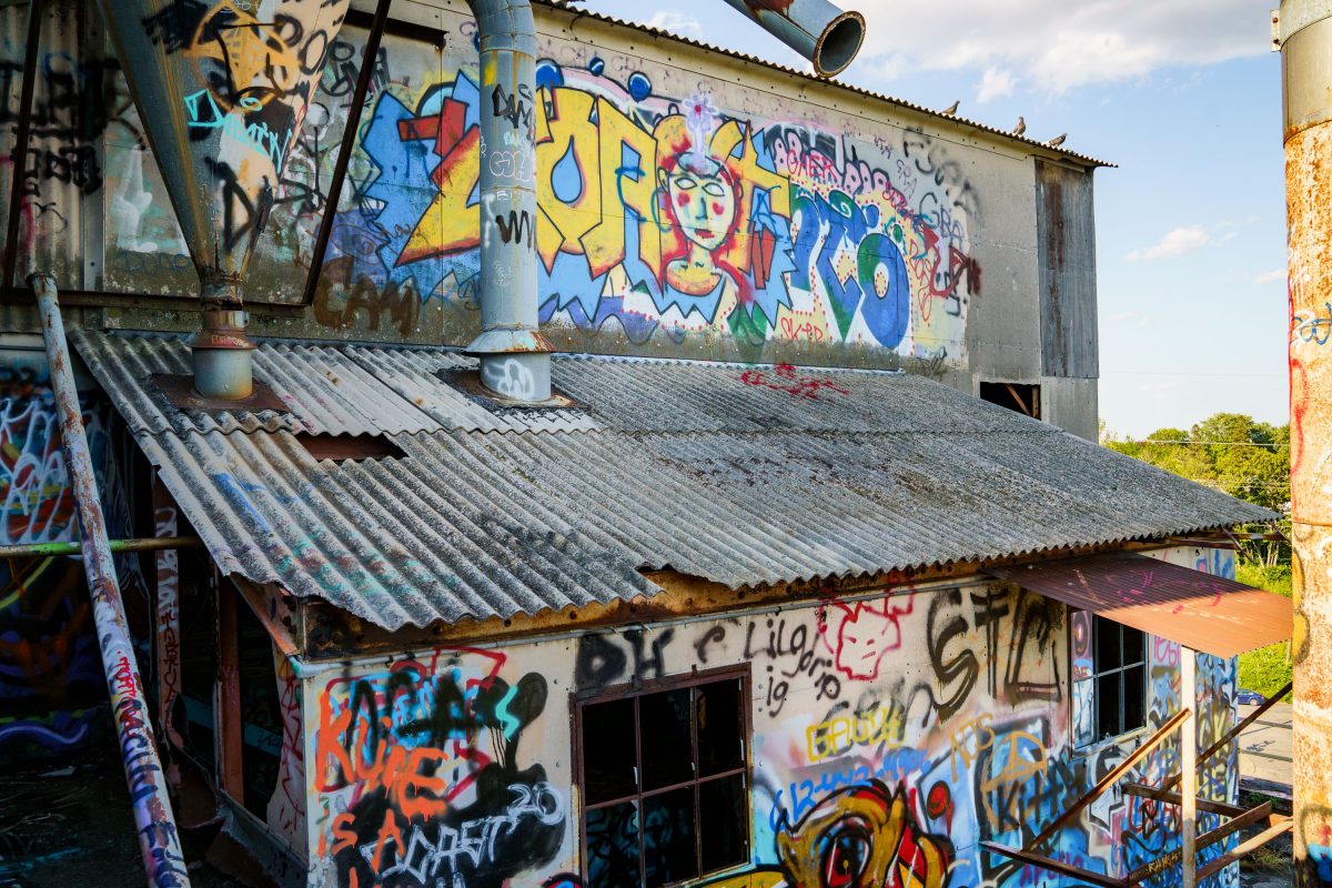 Abandoned industrial building with corrugated metal roof covered in colorful graffiti at the Fruen Mill.