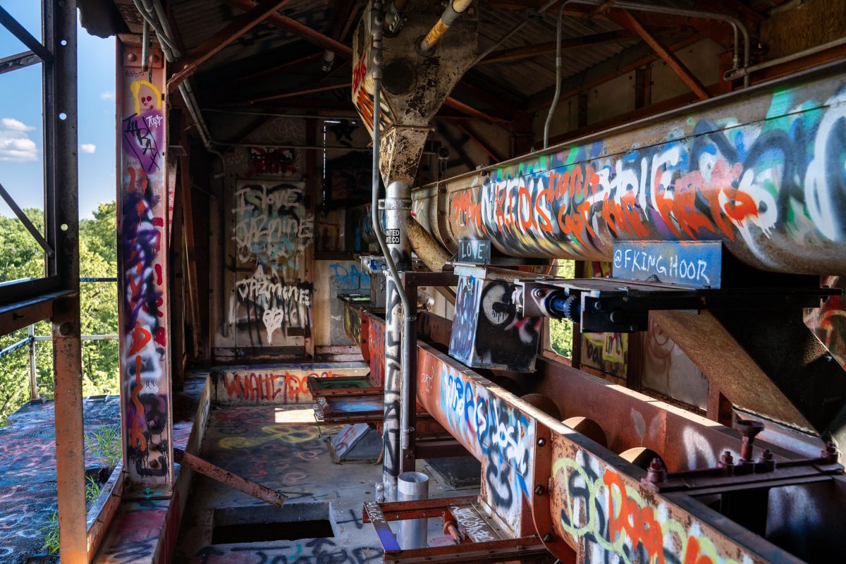 Interior of abandoned Fruen Mill in Minneapolis showing rusted industrial equipment covered in colorful graffiti.
