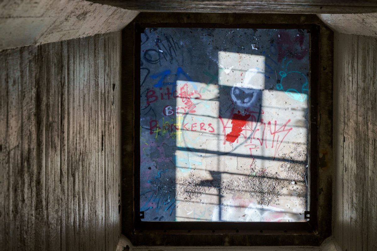 Weathered brick wall with multicolored graffiti and window shadow at abandoned Fruen Mill, Minneapolis.