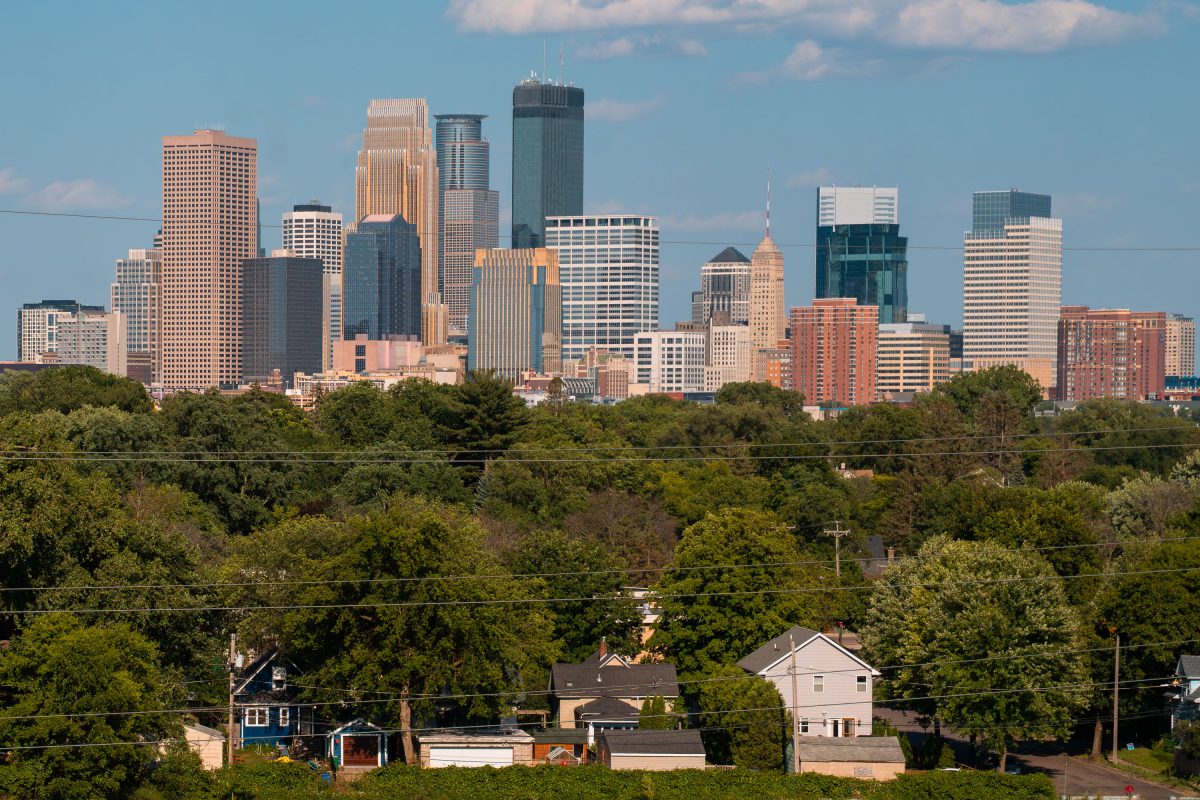 Minneapolis skyline with residential neighborhood and trees in foreground.