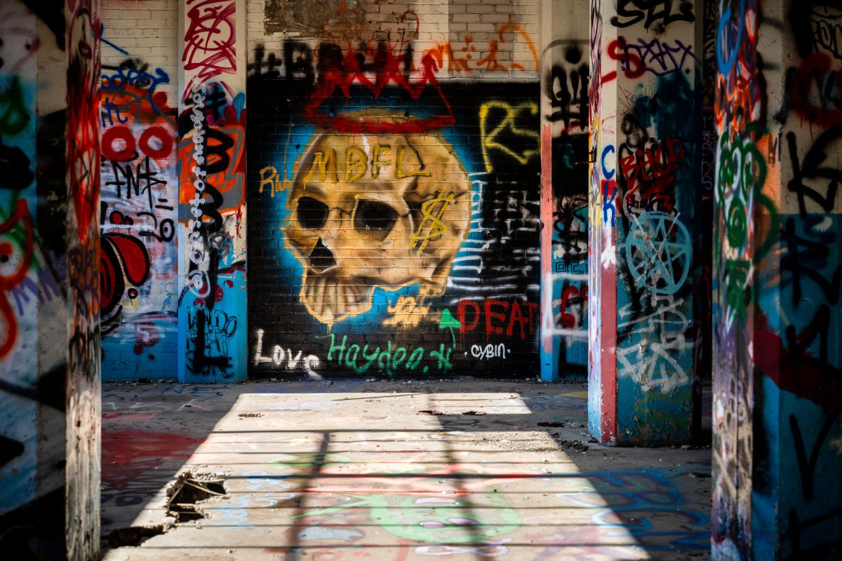 Abandoned Fruen Mill interior with yellow skull graffiti art and colorful tags on brick walls.