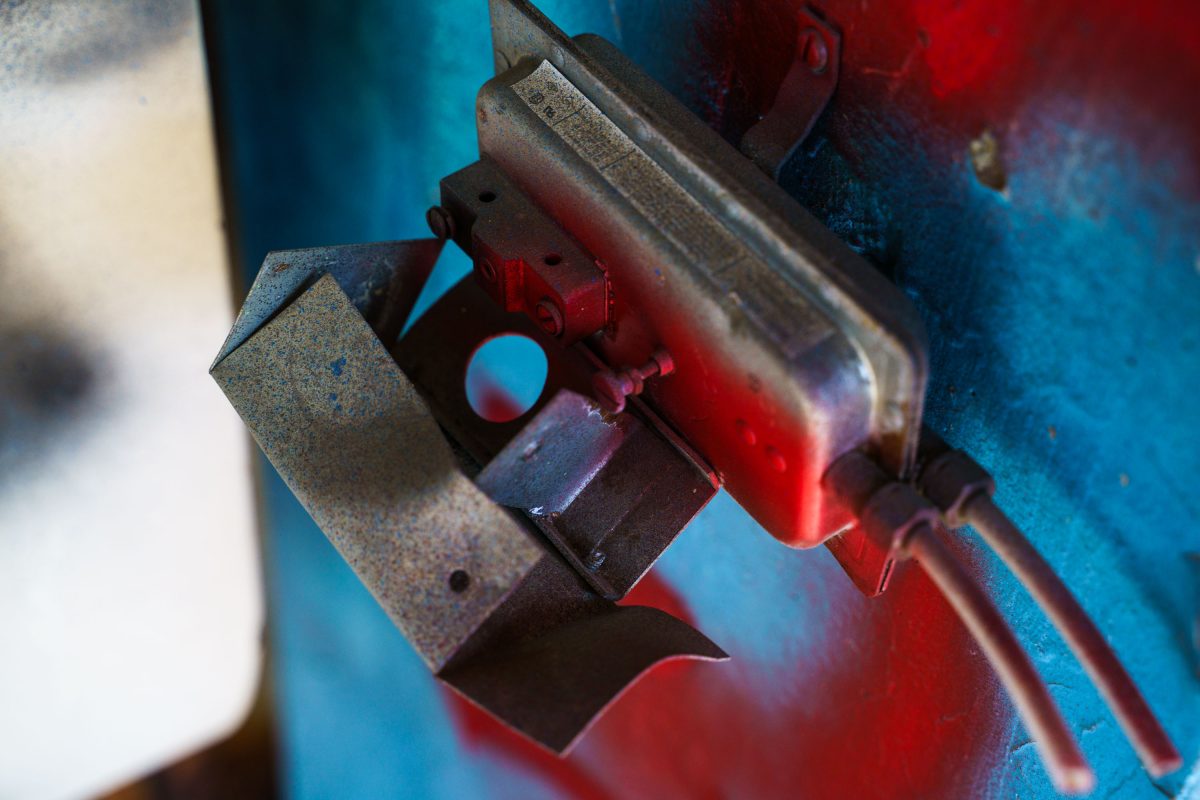 Close-up of rusted industrial machinery with red paint inside abandoned Fruen Mill.