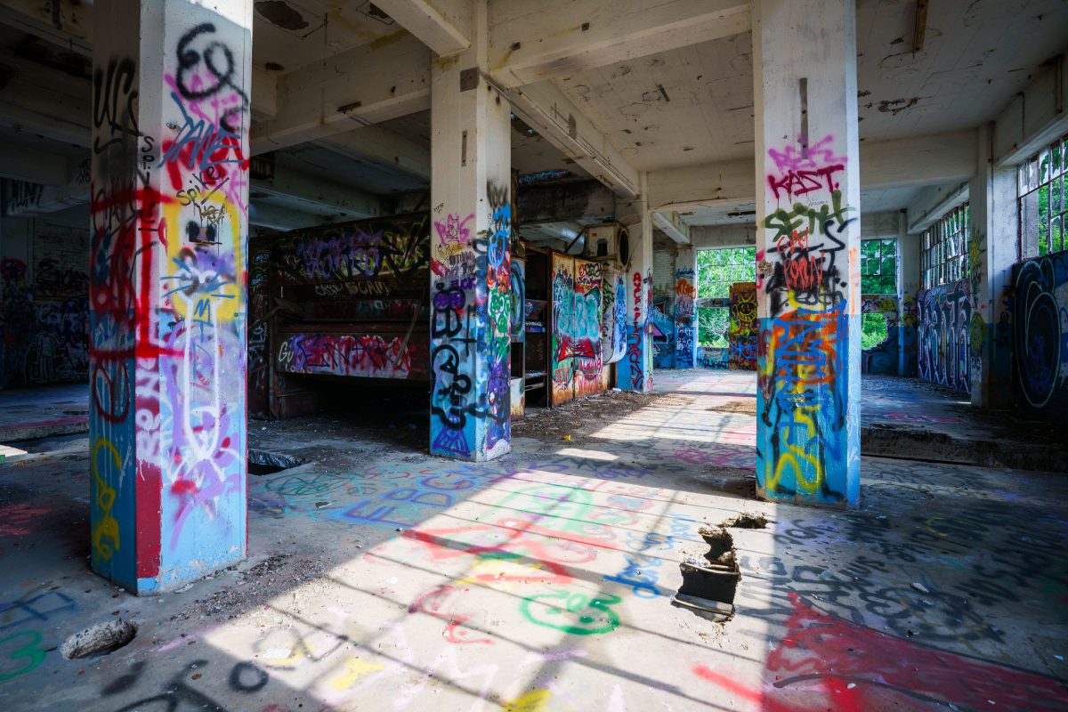 Abandoned Fruen Mill interior in Minneapolis with graffiti-covered structural columns and deteriorating floor.