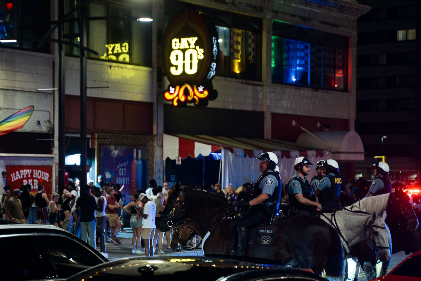 Mounted police officers are seen outside the Gay 90's bar in Minneapolis on July 24, 2022. The Gay 90's is a long-standing LGBTQ+ establishment in the city's downtown area, known for its nightlife. The presence of mounted police is common during public events or gatherings to maintain order and ensure safety. This image was taken during a period of heightened social awareness in Minneapolis following the murder of George Floyd in 2020, though the specific reason for the police presence on this particular night is not specified.