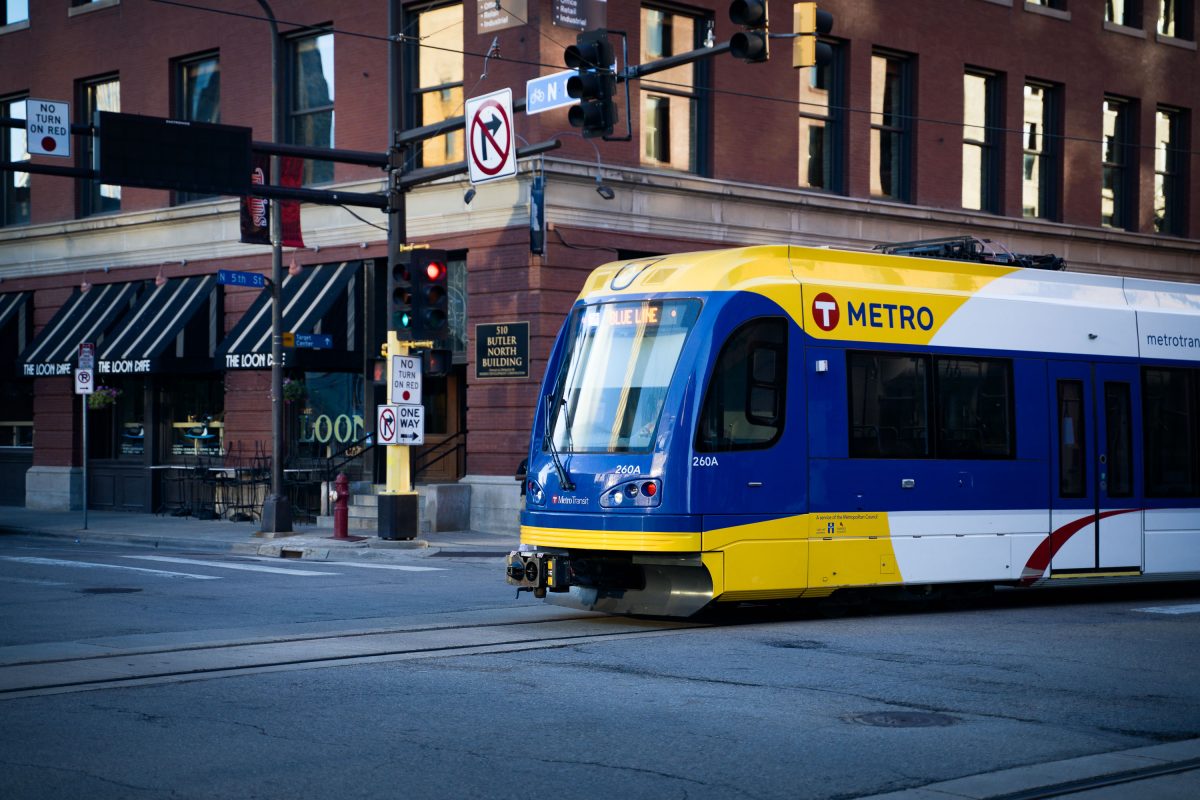 A blue and yellow METRO Blue Line light rail train travels through the Warehouse District in downtown Minneapolis.