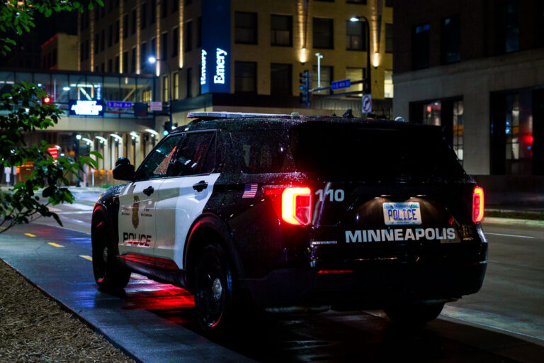 Minneapolis Police Squad Car on 7th Street South 1 A Minneapolis Police Department squad car is parked on 7th Street South in downtown Minneapolis, near the Emery building. The vehicle, marked with "Police" and "Minneapolis," is a common sight in the city's urban core, where it serves to maintain public order and respond to emergencies. The presence of a police vehicle in this area, particularly given the "MinneapolisUprising" keyword, may allude to the heightened tensions and public events that have occurred in the city. The "Emery" building, a structure that has been part of the downtown Minneapolis landscape for many years, is visible in the background.