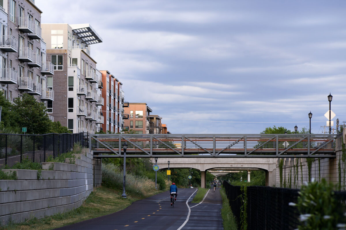 The Midtown Greenway in Minneapolis is a 5.5-mile-long trail developed on a former railroad corridor, providing a vital artery for cyclists and pedestrians through the city. Adjacent apartment buildings, constructed in recent years, demonstrate the integration of modern residential development with the trail's active use. A pedestrian bridge spans the greenway, connecting neighborhoods and enhancing access to this popular urban path.