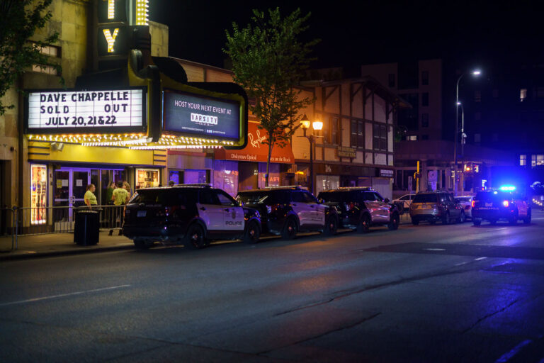 Dave Chappelle Show, Police Cars at Varsity Theater, Minneapolis 2 Police vehicles were stationed outside the Varsity Theater in Minneapolis on July 20, 2022, during the first night of a sold-out engagement by comedian Dave Chappelle. The Varsity Theater, a historic venue in the Dinkytown neighborhood, has a long-standing reputation for hosting live performances and film screenings. The visible police presence suggests a heightened security measure, possibly in response to past controversies surrounding Chappelle's performances or general public safety concerns.