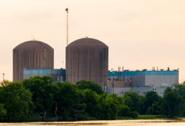 The twin concrete containment domes pictured here belong to the Prairie Island Nuclear Generating Plant, located along the Mississippi River just northwest of Red Wing, Minnesota. Operated by Xcel Energy, the facility houses two pressurized-water reactors that began commercial operation in the early 1970s. The domed structures serve as reinforced containment buildings, designed to house the reactor vessels and critical safety systems.

Set against the river and surrounded by dense tree cover, the plant sits adjacent to the Prairie Island Indian Community, whose proximity has been central to public discussions about nuclear safety, spent-fuel storage, and long-term energy planning in Minnesota. The low evening light in this image highlights the muted textures of the domes and the teal-panel cladding of the turbine and support buildings, offering a clear view of one of the state’s most prominent pieces of energy infrastructure.