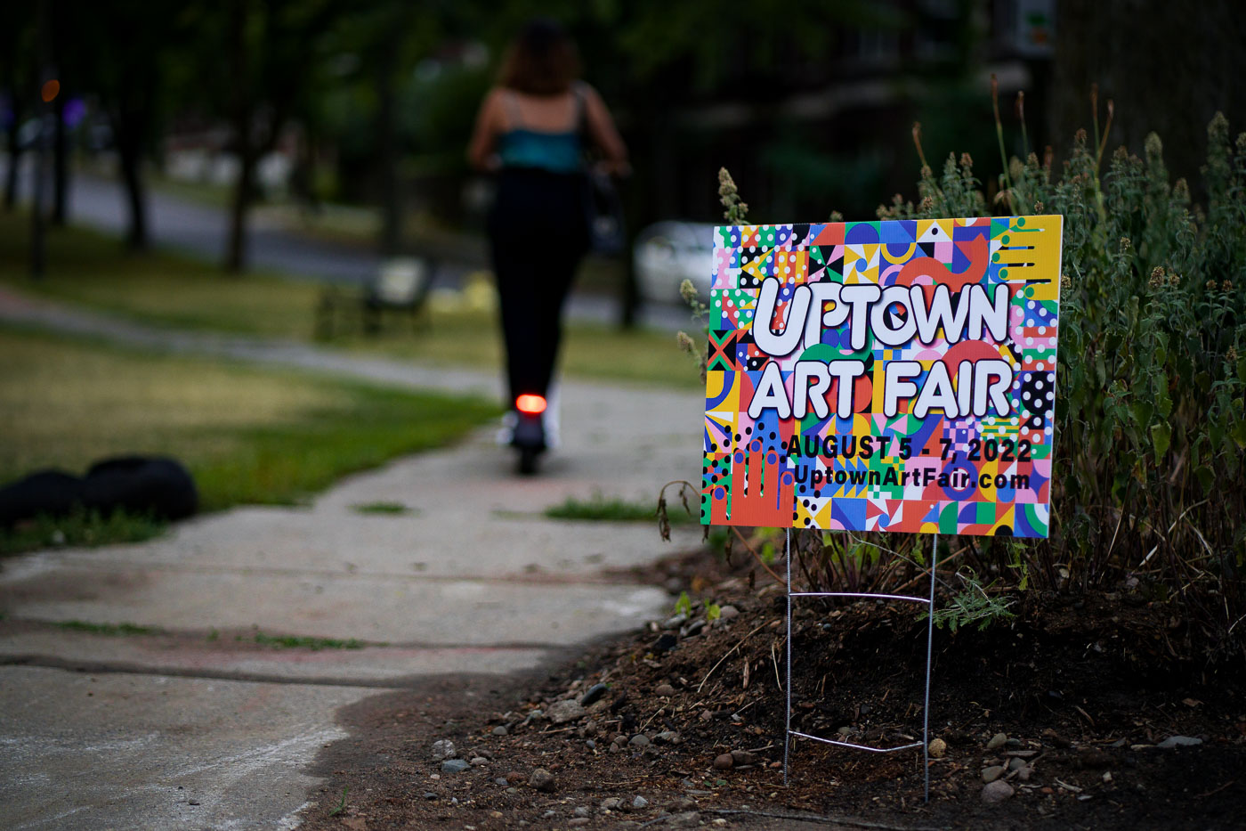 A sign announces the Uptown Art Fair in Minneapolis, which took place from August 5-7, 2022. This annual event is a juried exhibition that draws artists and visitors from across the country to the Uptown neighborhood. The fair has been a significant cultural fixture in Minneapolis, contributing to the area's reputation as a vibrant arts district and drawing substantial crowds.