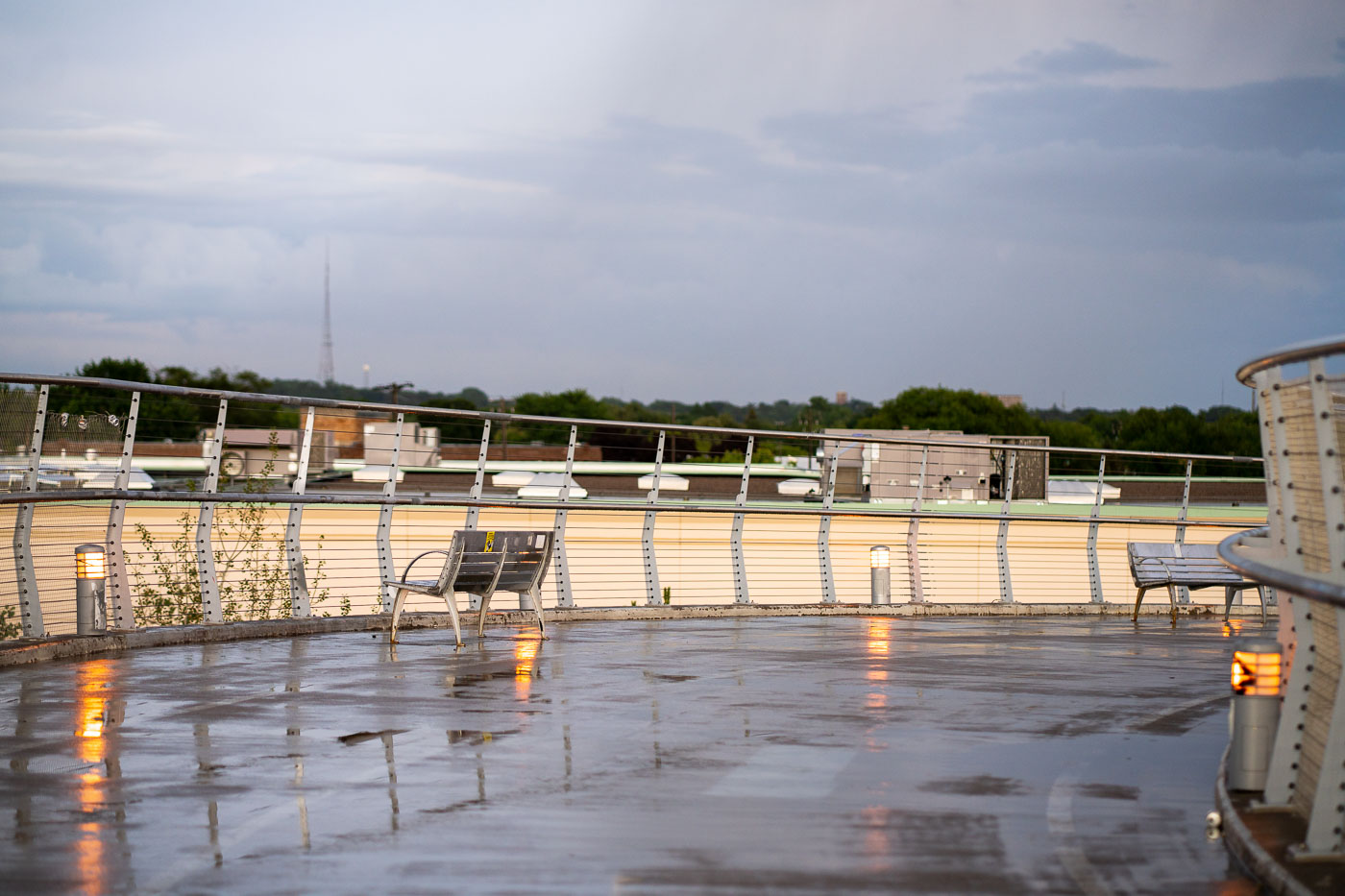 The Martin Olav Sabo Bridge in Minneapolis, also known as the "Hiawatha Line Bridge," is a pedestrian and bicycle bridge that opened in 2002. It spans the Hiawatha Avenue Light Rail corridor, connecting the Longfellow and Cooper neighborhoods and serving as a crucial link for non-motorized transit. The bridge's design includes aesthetic features like integrated lighting and seating areas, intended to enhance the user experience. The "wet deck" in the title refers to the bridge's surface, glistening with reflections after recent rain.