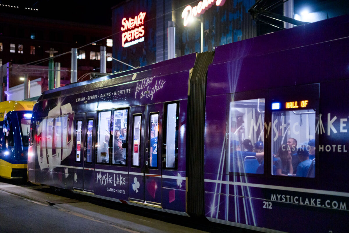 A Mystic Lake casino wrapped light rail train at the Warehouse District-Hennepin LRT station during a Twin's game.