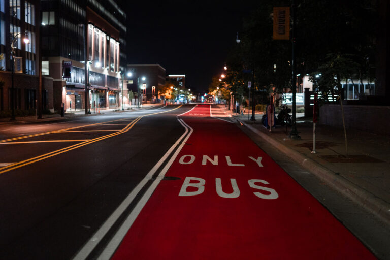 Red Bus Lane on Chicago Avenue at Nigh 2 A dedicated red bus-only lane runs along Chicago Avenue in Minneapolis, part of the city’s recent investments in transit priority corridors. These painted lanes are designed to give buses consistent travel times through dense urban segments, especially during peak hours, and they align with regional plans to improve service reliability on key north–south routes. Late at night the corridor is quiet, with the reflective pavement markings and overhead lighting emphasizing the straight line of the transit path through the Midtown area.