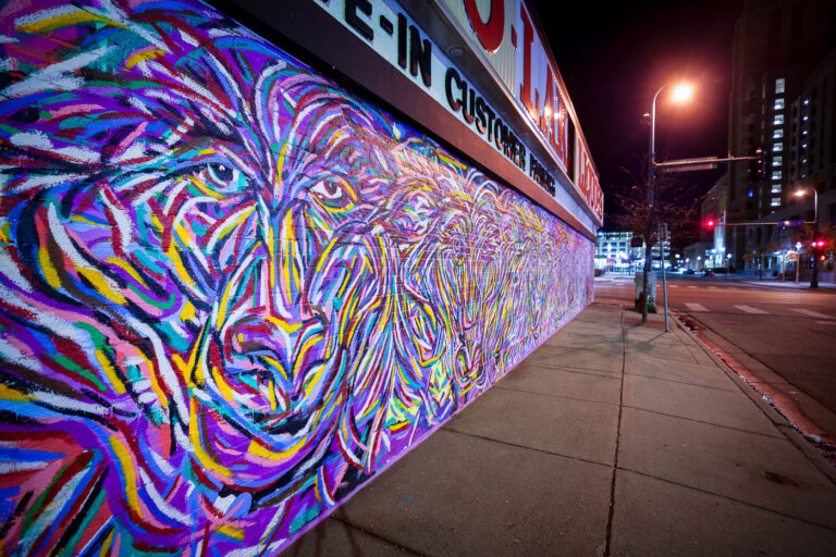 Jimmy Longoria mural on Chicago Lake Liquors in Minneapolis 3 A new mural from Jimmy Longoria wraps around the Chicago-Lake Liquors building and covering the front metal shutters.