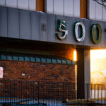 5001 Building During Southgate Demolition 2 The address numbers 5001 hang damaged and partially peeled from the exterior of the former Southgate Office Tower in Bloomington, Minnesota. Shot during the late-afternoon winter light, the sign shows the wear of a building already deep into demolition. The brick façade, fencing, and scattered debris reflect the final stages of teardown at the long-vacant 1960s-era tower that once stood near I-494 and Portland Avenue.