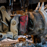 Excavator Attachment at Southgate Demolition 1 A close-up view of a hydraulic excavator’s quick-coupler and demolition attachment during the teardown of the former Southgate Office Tower in Bloomington, Minnesota. The worn steel, hydraulic lines, and layers of dust and debris show the heavy strain placed on equipment during large-scale structural demolition. Piles of shattered concrete, insulation, and twisted metal surrounding the attachment reflect the ongoing dismantling of the mid-century office complex.