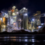 Graymont Lime Plant on the Fox River, Green Bay 3 The Graymont lime processing plant along the Fox River in Green Bay, Wisconsin, illuminated during nighttime operations. The facility’s network of silos, conveyors, and dust-collection towers stands out against the dark sky, with steam drifting from active kilns and processing units. Reflections from the plant’s industrial lighting shimmer across the frozen river surface, highlighting the site’s role in the region’s long-standing manufacturing and mineral production corridor.