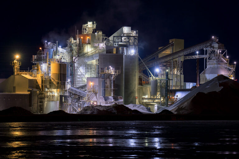 Graymont Lime Plant on the Fox River, Green Bay 3 The Graymont lime processing plant along the Fox River in Green Bay, Wisconsin, illuminated during nighttime operations. The facility’s network of silos, conveyors, and dust-collection towers stands out against the dark sky, with steam drifting from active kilns and processing units. Reflections from the plant’s industrial lighting shimmer across the frozen river surface, highlighting the site’s role in the region’s long-standing manufacturing and mineral production corridor.
