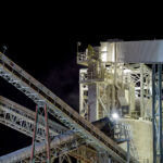 Lime Processing Infrastructure at Night 2 A detailed nighttime view of the conveyor towers and processing equipment at the Graymont lime plant in Green Bay, Wisconsin. The illuminated catwalks, ducts, and steel trusses highlight the facility’s continuous material-handling system, where crushed limestone moves through enclosed conveyors toward the plant’s kilns and storage silos. Fine dust, visible in the lights near the upper platforms, reflects the industrial character of a site that has served the region’s construction and manufacturing sectors for decades.